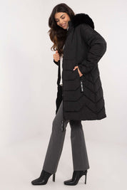 Woman wearing Elvarra Quilted Winter Down Coat, knee-length with detachable fur hood, showcasing stylish and warm urban autumn outfit.