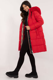 Woman wearing a red Arden Quilted Longline Winter Jacket with detachable hood and fur trim, offering warmth and style for winter.