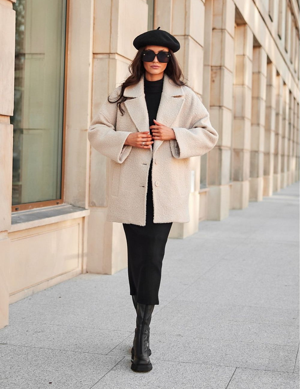 Woman wearing a stylish beige quilted button-up jacket with classic collar and black outfit, walking confidently on a city street.