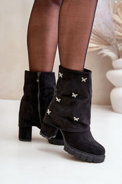 Black suede foldover boots with butterfly accents and side zipper, styled with black tights, perfect for autumn-winter fashion.