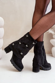Black suede boots with foldover design and silver floral accents, featuring chunky heels and side zippers for modern style and comfort.