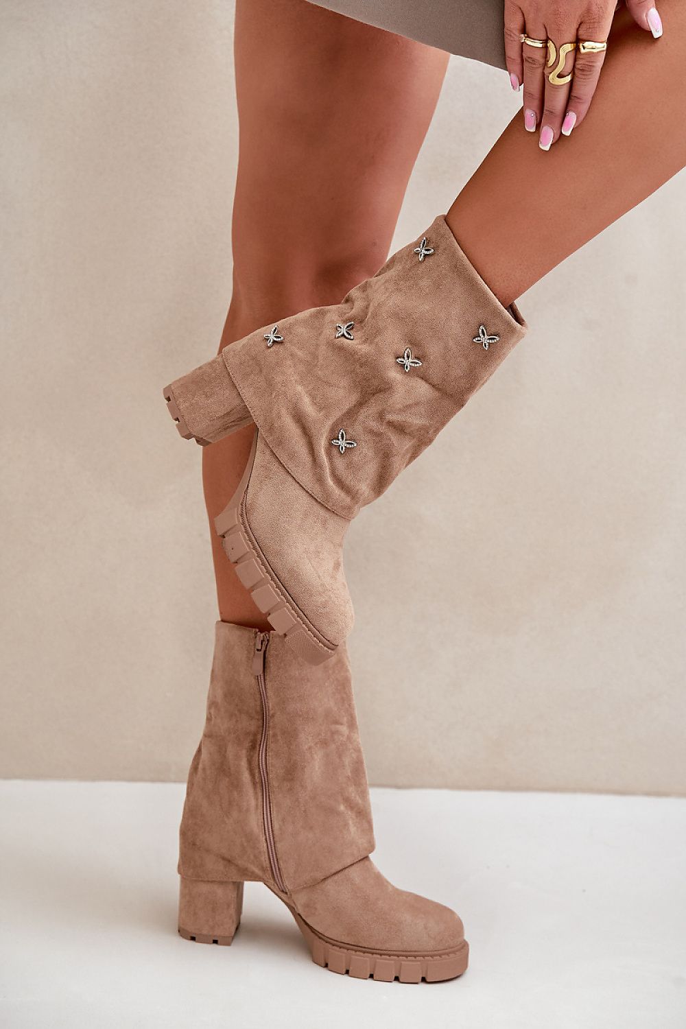 Woman wearing tan suede boots with decorative star studs and block heels, showcasing fall fashion style.