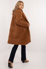 Woman wearing a stylish brown knee-length winter coat with black jeans and tan boots, highlighting a cozy and fashionable look.