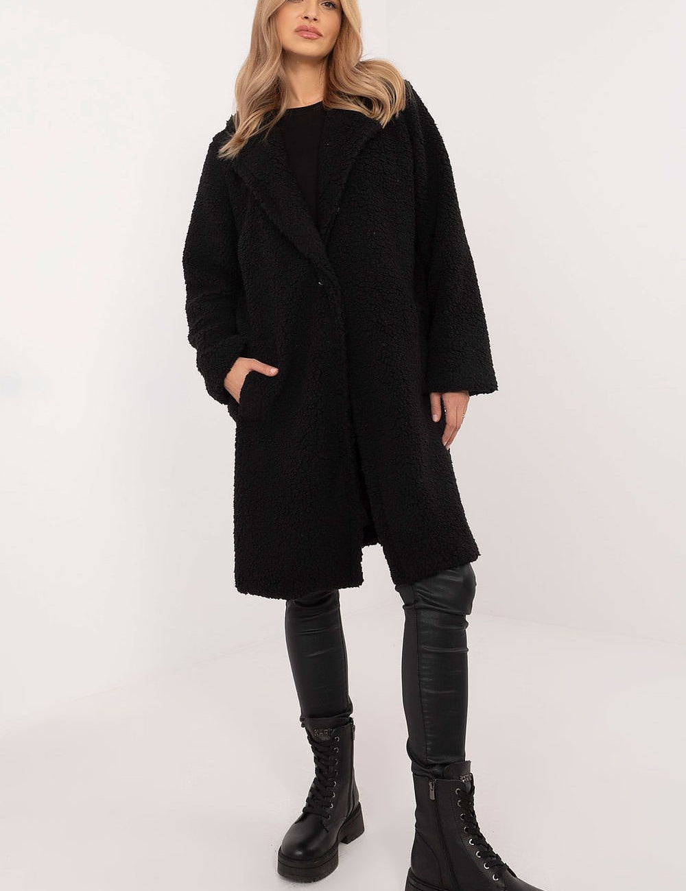 Woman wearing the Elantra Pre-Knee Winter Coat, black, with a classic cut and smooth silhouette, paired with leather pants and boots.