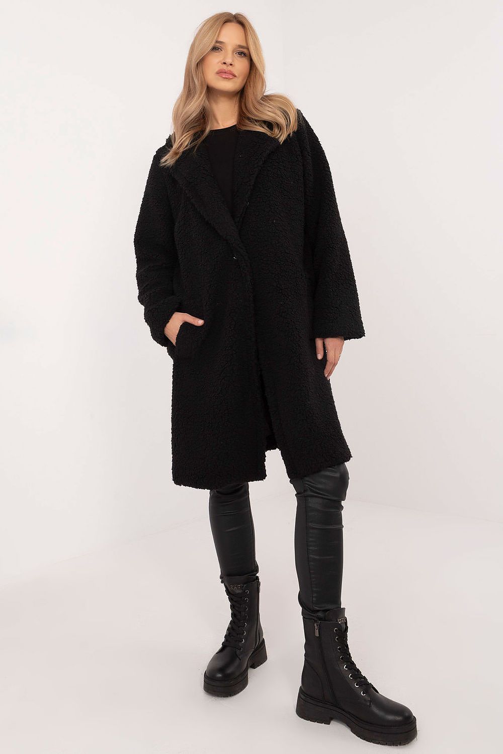 Woman wearing the Elantra Pre-Knee Winter Coat, black, with a classic cut and smooth silhouette, paired with leather pants and boots.