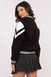 Woman wearing a black and white Marvessa Press-Stud Bomber Jacket with sporty design and pleated skirt, seen from the back.