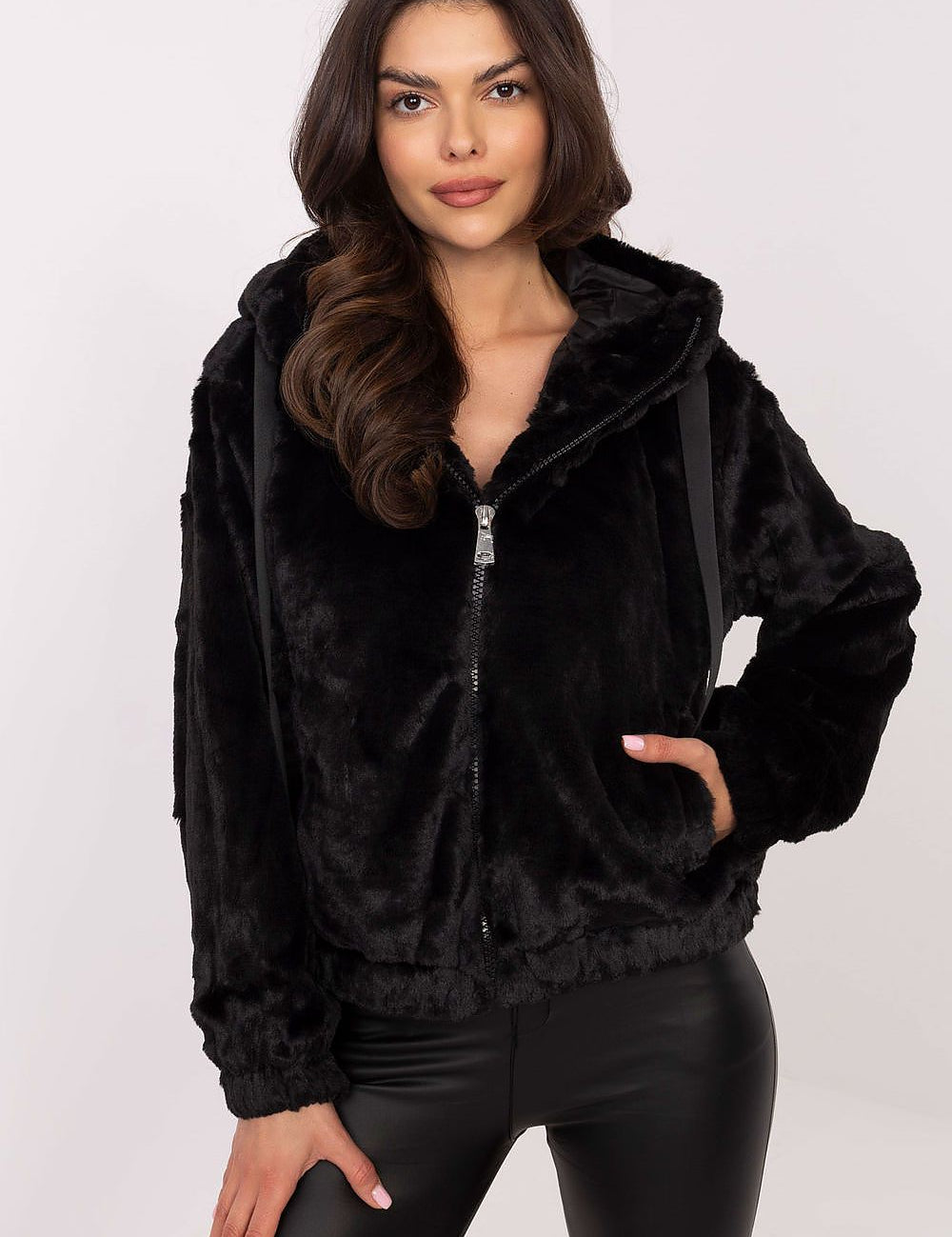 Woman wearing black Corvalyn Hooded Teddy Bear Zip Jacket, features soft texture, hood, ZIP closure, and adjustable waist ties.