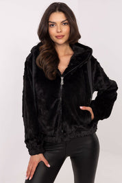 Woman wearing black Corvalyn Hooded Teddy Bear Zip Jacket, features soft texture, hood, ZIP closure, and adjustable waist ties.