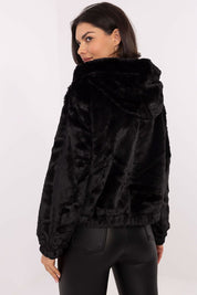 Woman wearing black Corvalyn Hooded Teddy Bear Zip Jacket, featuring plush texture, hood, and adjustable waist ties, viewed from the back.