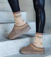 Person wearing Tavelya Embroidered Winter Snow Boots with floral socks, showcasing slip-on design, rubber sole, and low heel.