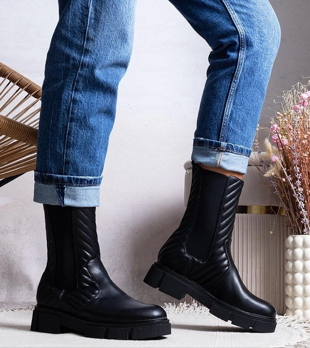 Zarelda treaded ankle boots with thick sole and decorative strap, paired with rolled jeans, perfect for autumn and winter warmth.