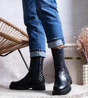Person wearing Zarelda treaded ankle boots with thick sole and ankle strap, paired with jeans, indoors.