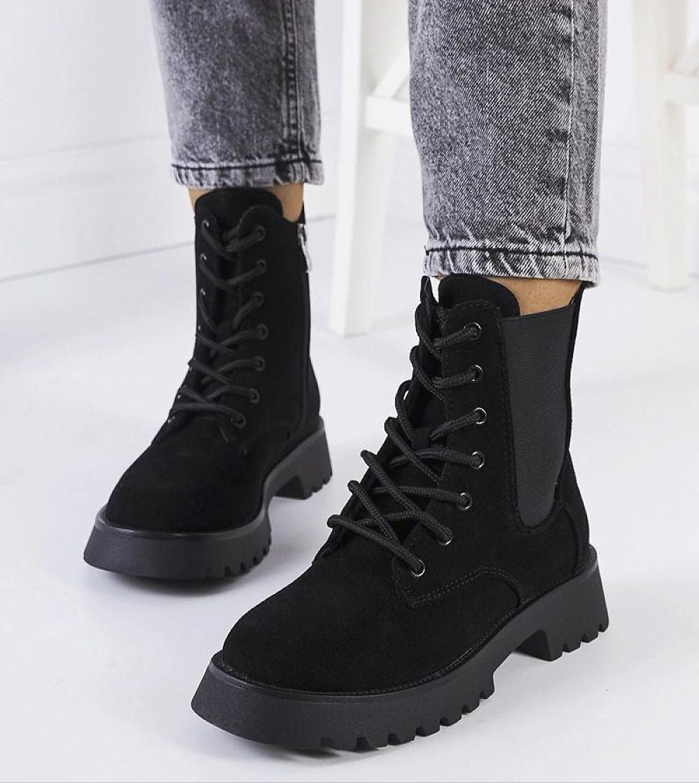 Black Everleigh Ridge Winter Boots with chunky soles and laces, paired with gray jeans, showcasing cold-weather style and practicality.