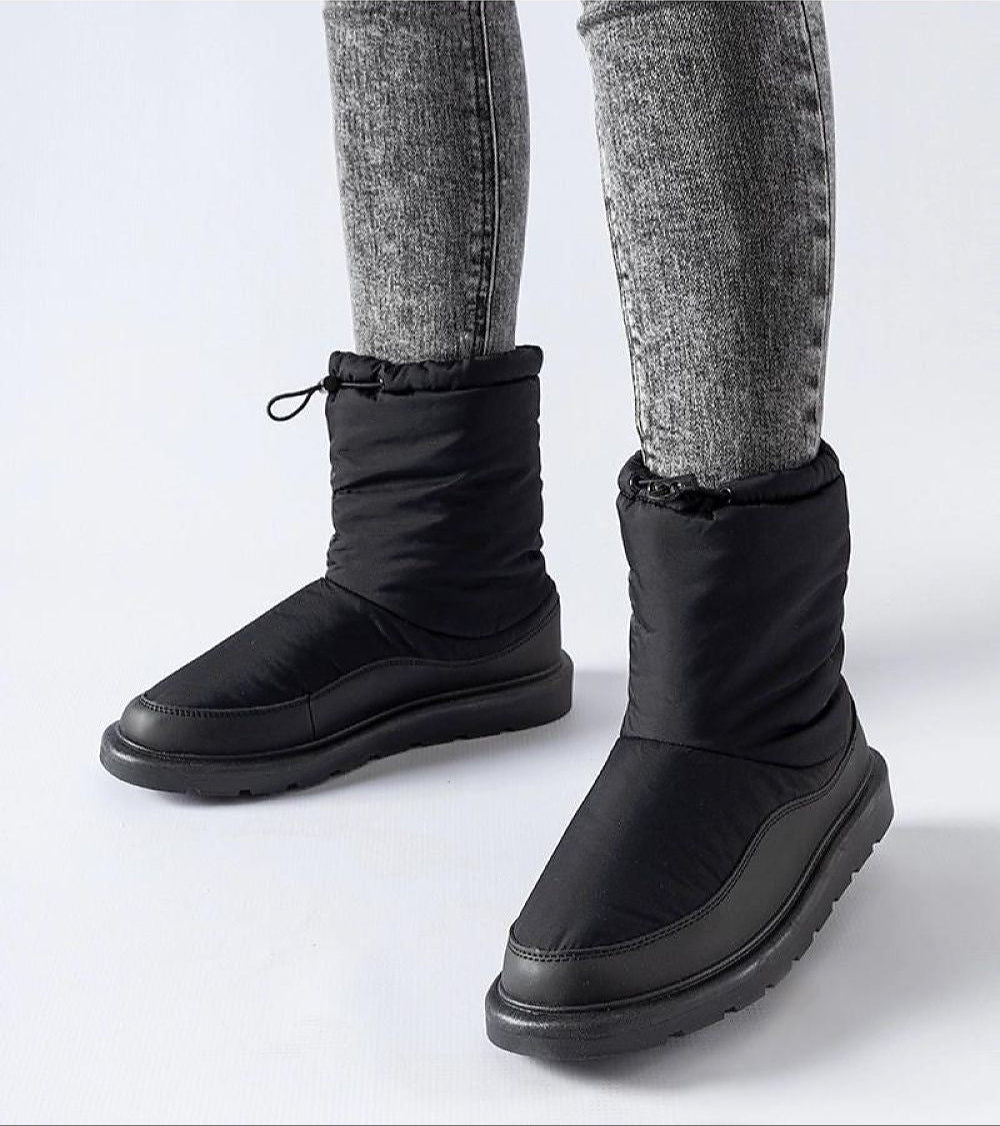 Person wearing Sylverra Slip-On Winter Snow Boots with black insulated upper and waterproof sole, ideal for icy conditions.