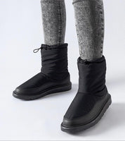 Person wearing Sylverra Slip-On Winter Snow Boots with black insulated upper and waterproof sole, ideal for icy conditions.