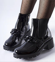 Velandra Glossy Buckle Boots in patent-effect eco leather with metal buckle, insulated for warmth, on a model with patterned tights.