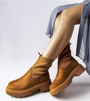 Model wearing Solmare Eco-Suede Slip-On Boots in brown with medium heel and rubber sole, styled with a casual grey skirt.