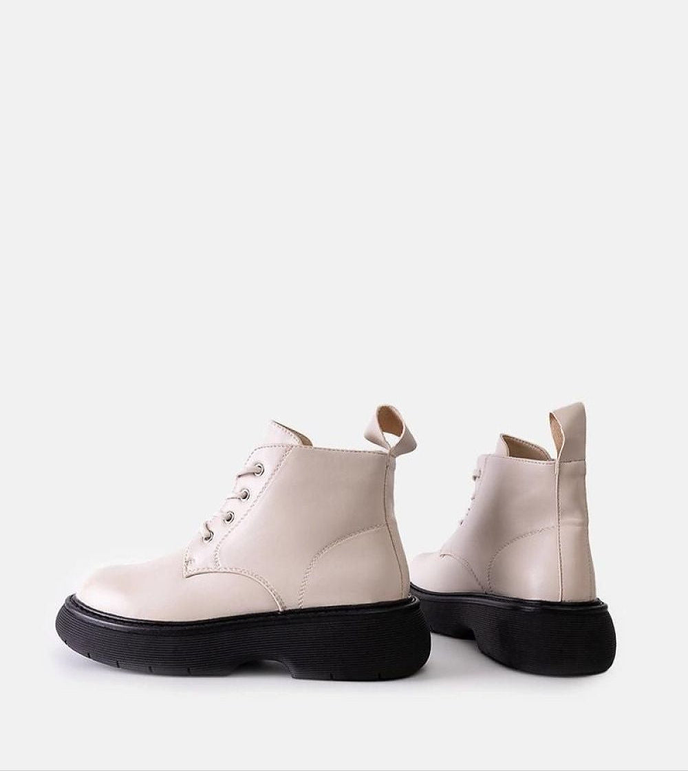 Matte white lace-up boots with thick black soles, offering a bold silhouette and urban flair from Solvaira's fall collection.