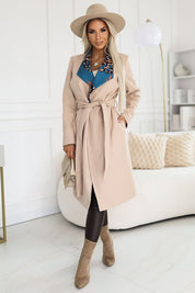 Woman wearing Corvalisse Belted Warm Lined Coat with colorful inserts, standing in a modern room, showcasing elegant and warm winter fashion.