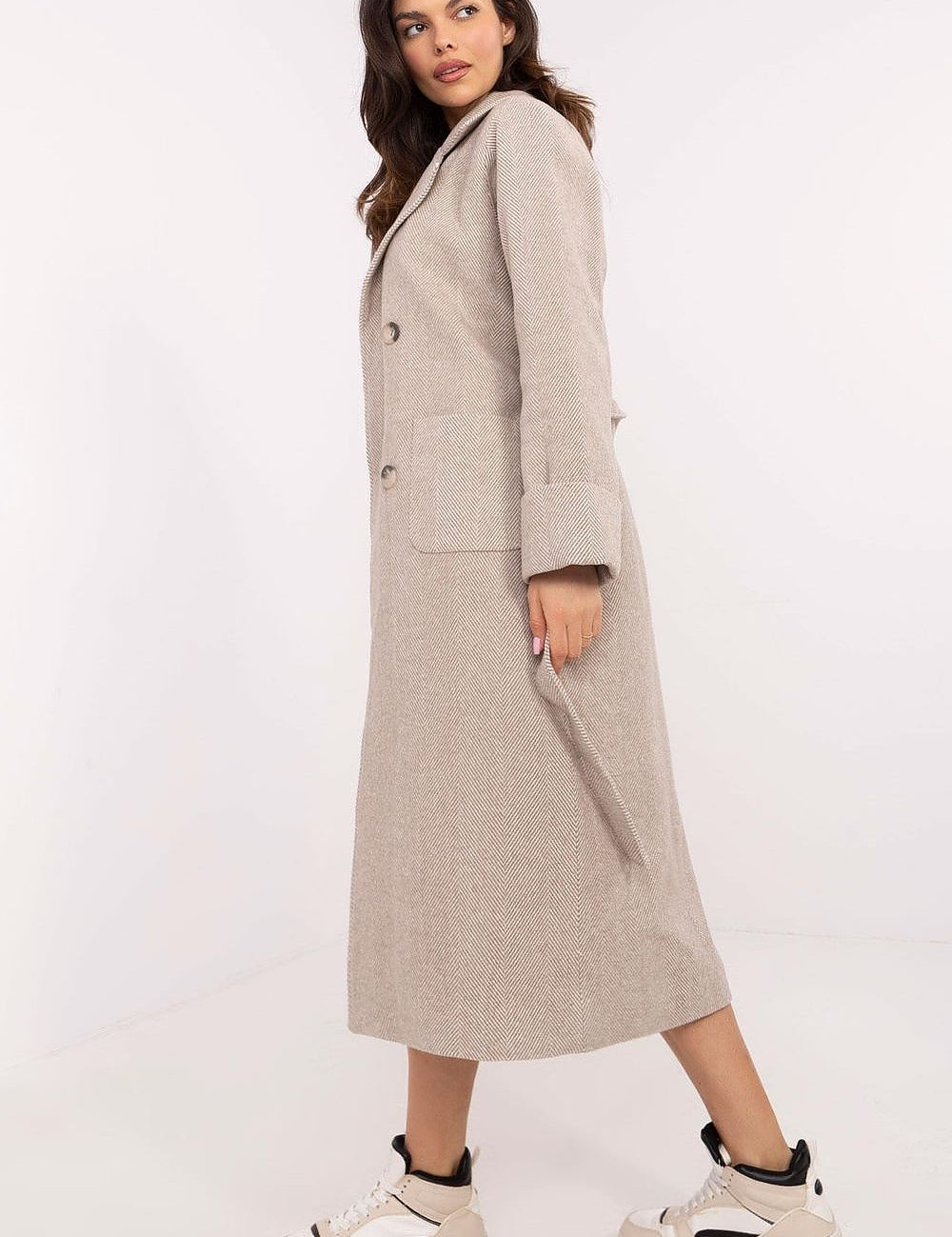 Woman wearing Selvarane long double-breasted wool coat with belted waist and fine stripes, side view, paired with sneakers.