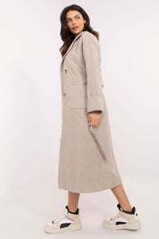 Woman wearing Selvarane long double-breasted wool coat with belted waist and fine stripes, side view, paired with sneakers.