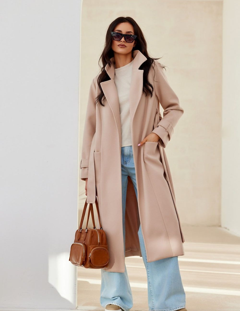Model wearing Loravinne Belted Long-Sleeve Lined Coat, styled with sunglasses, bag, and jeans for a chic, everyday look.