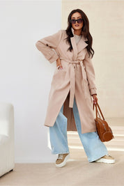 Woman wearing Loravinne Belted Long-Sleeve Lined Coat with jeans and carrying a handbag, showcasing elegant and practical fashion.
