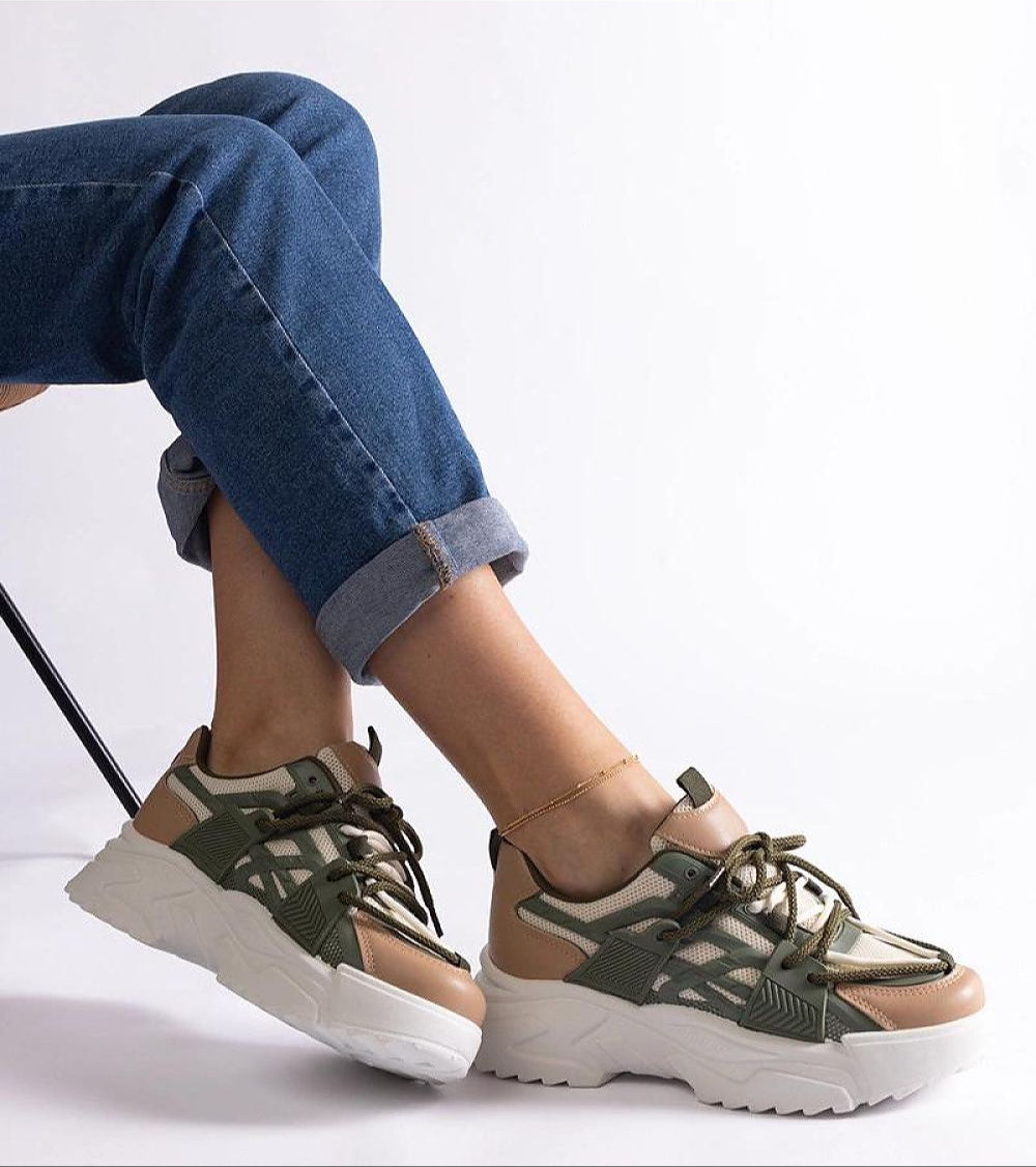 Person wearing Orlira Sage-Toned Urban Sneakers with sculpted rubber sole and lace-up style, paired with rolled-up jeans for a casual look.