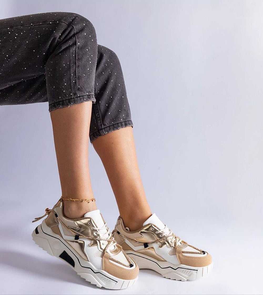 Woman wearing stylish beige and white sneakers with black speckled jeans, showing a modern casual outfit.