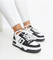 Person wearing Noira platform sneakers in black-and-white eco-leather with thick soles, showcasing modern design and comfort.