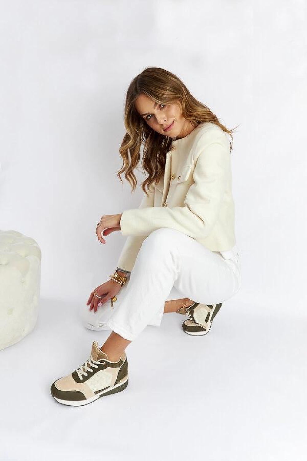 Woman wearing casual outfit with beige and green sneakers, posing indoors.