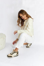 Woman wearing casual outfit with beige and green sneakers, posing indoors.