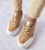 Person wearing Ismerra suede platform lace sneakers with eco suede upper and white sole on a textured surface.