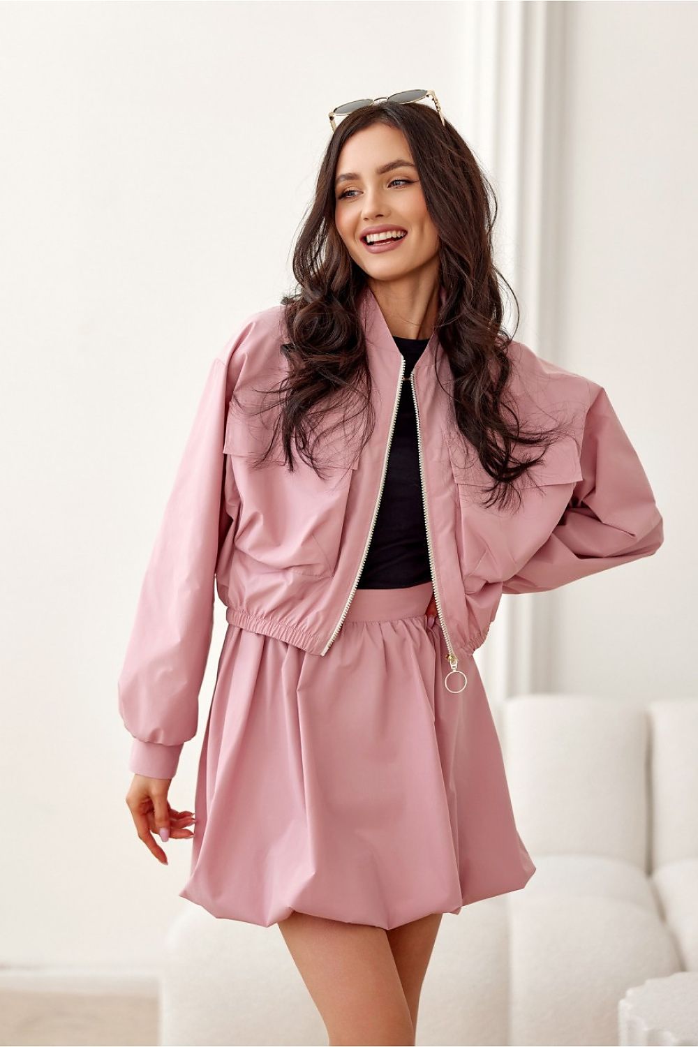 Woman wearing pink Valserra lined bomber jacket with casual skirt, perfect for versatile streetwear fashion.
