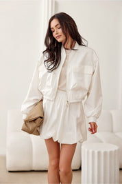Woman wearing Valserra lined bomber jacket with a casual dress, showcasing the minimalist design and side flap pockets.