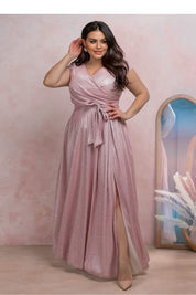 Auravelle Plus Size Evening Dress in blush with wrap V-neck, high slit, modeled by woman standing in elegant room.