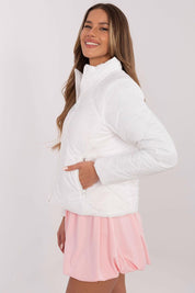 Woman wearing Morvianne Quilted Zip-Front Jacket in white, showcasing lightweight nylon and zippered pockets, styled with a pink skirt.