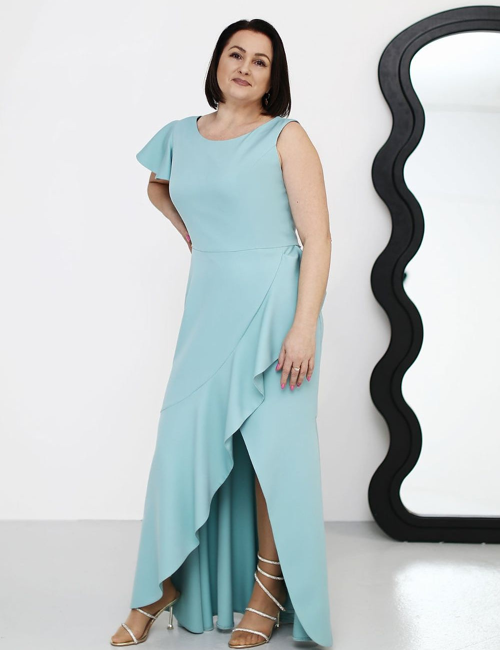 Plus Size Elvarise One-Shoulder Cocktail Dress with ruffle, asymmetrical design in soft blue, worn by a woman next to a curved mirror.