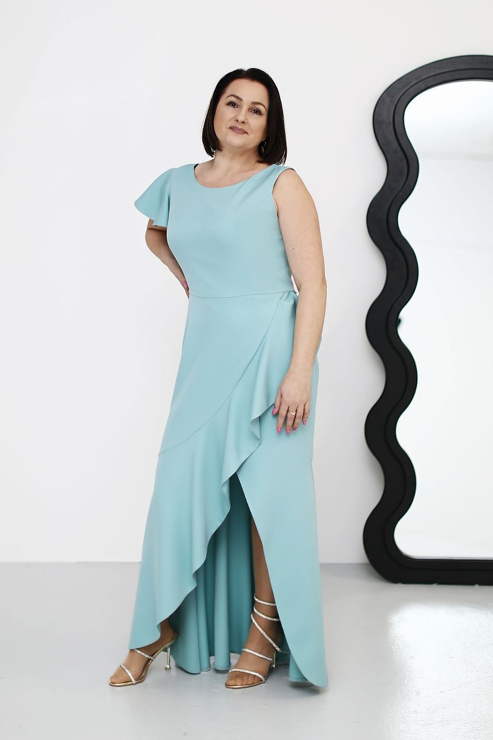 Plus Size Elvarise One-Shoulder Cocktail Dress with ruffle, asymmetrical design in soft blue, worn by a woman next to a curved mirror.