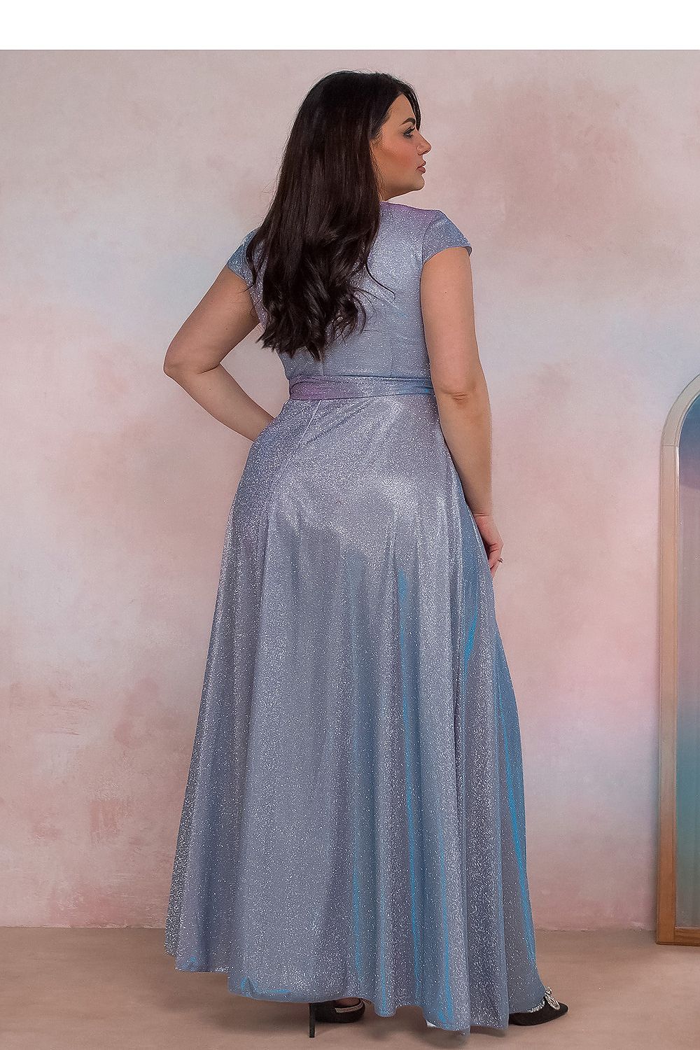Back view of a plus-size woman wearing a shimmering blue evening dress with cap sleeves, showcasing elegance and style.