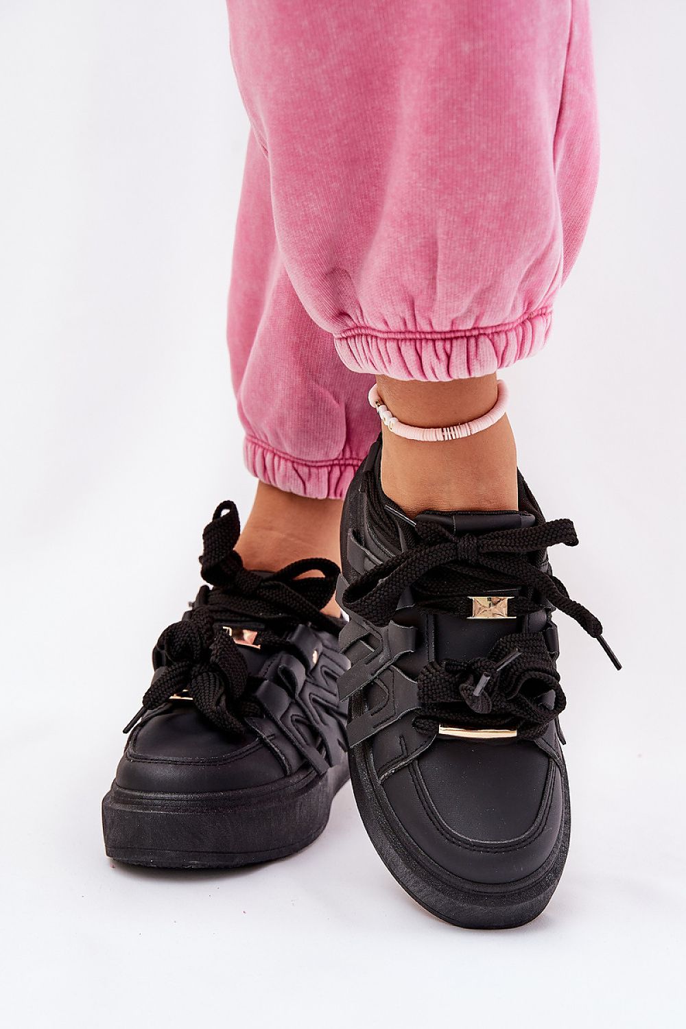 Person wearing Cernia Synthetic Platform Lace Sneakers in black with pink pants, showcasing contemporary streetwear style and comfort.