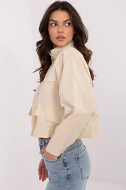 Woman wearing Corvaline lightweight windbreaker jacket in beige, side view, styled with blue jeans.