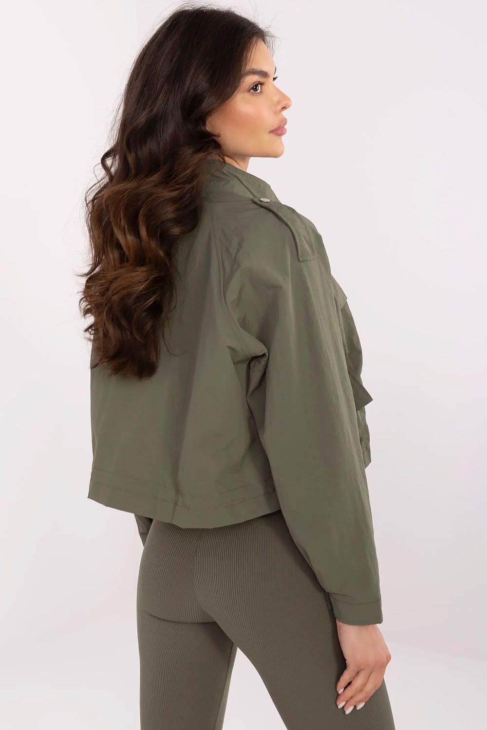 Woman wearing Corvaline windbreaker jacket in olive green, showing back view with epaulets. Perfect for spring and summer.