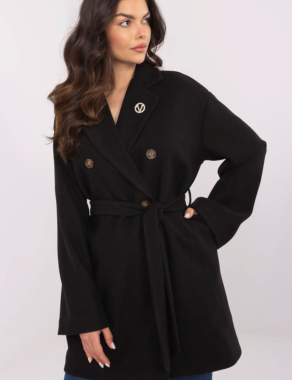 Woman wearing Selvarinne double-breasted short coat with waist tie and decorative brooch, showcasing a structured silhouette.