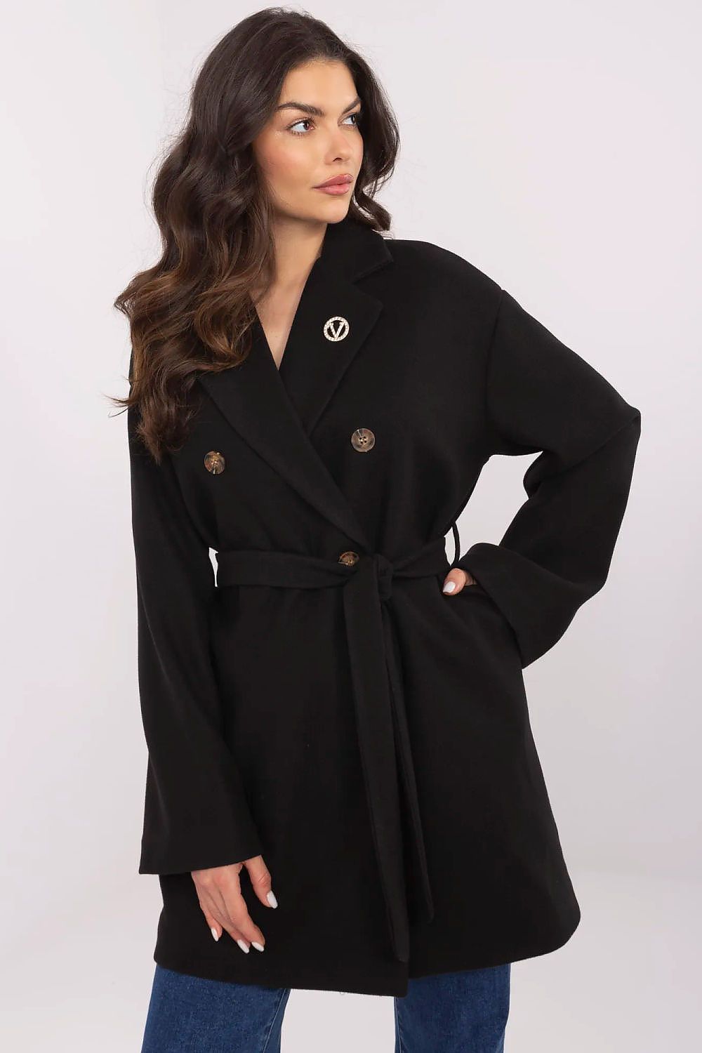 Woman wearing Selvarinne double-breasted short coat with waist tie and decorative brooch, showcasing a structured silhouette.