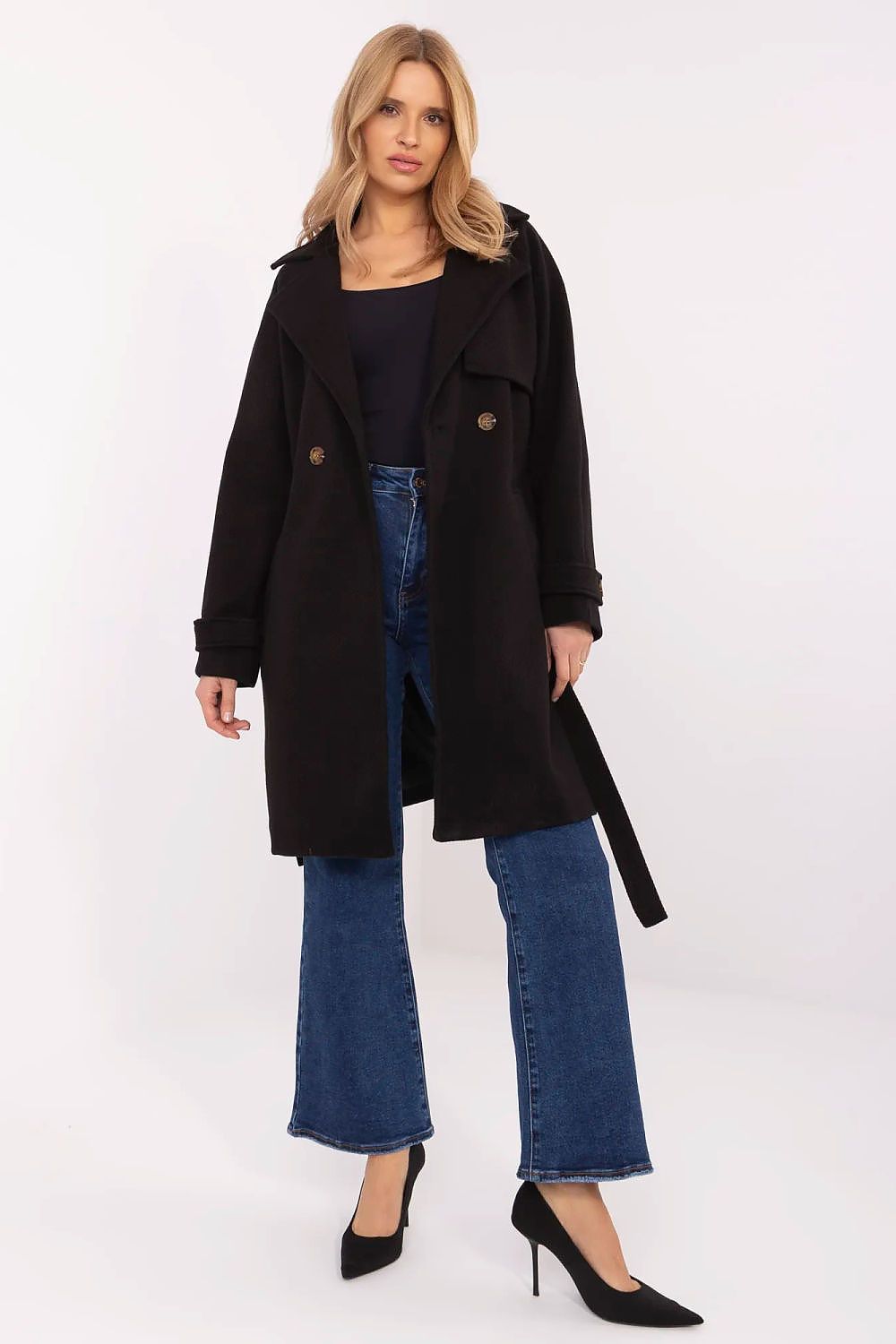 Woman wearing Corvanne double-breasted belted coat in black, styled with blue jeans and black heels for a chic, modern look.