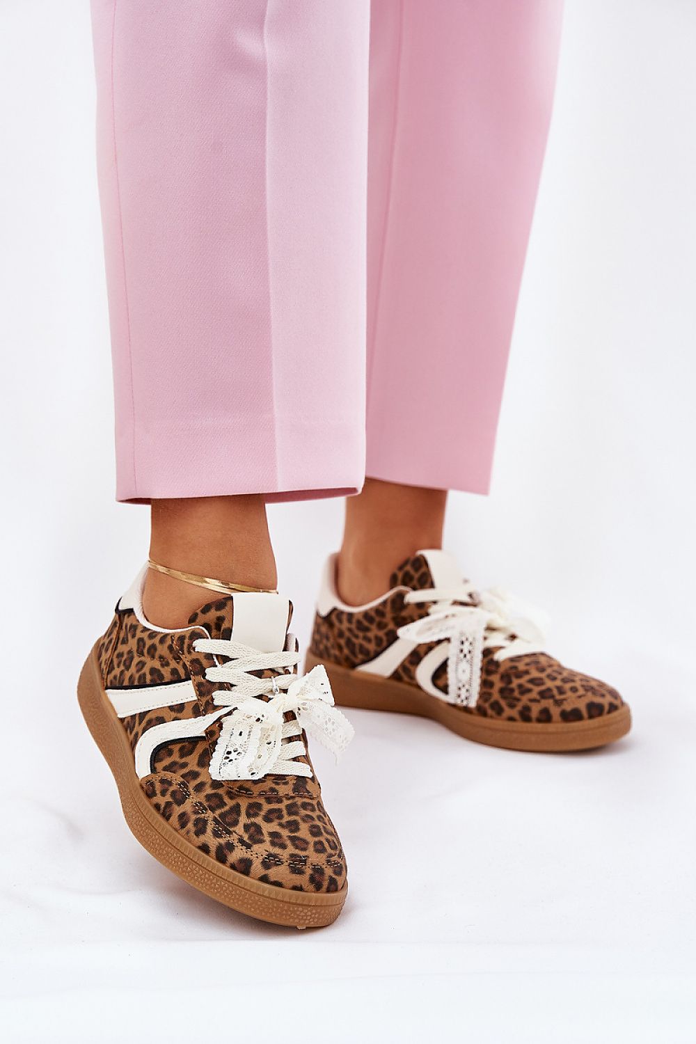 Model wearing pink pants with leopard print sneakers featuring white laces and a lace accent, showcasing Zyrmira's stylish design.