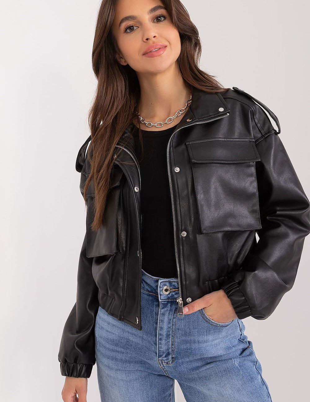 Woman wearing Arvenique Eco-Leather Short Jacket with front flap pockets and shoulder epaulettes, styled casually with jeans.