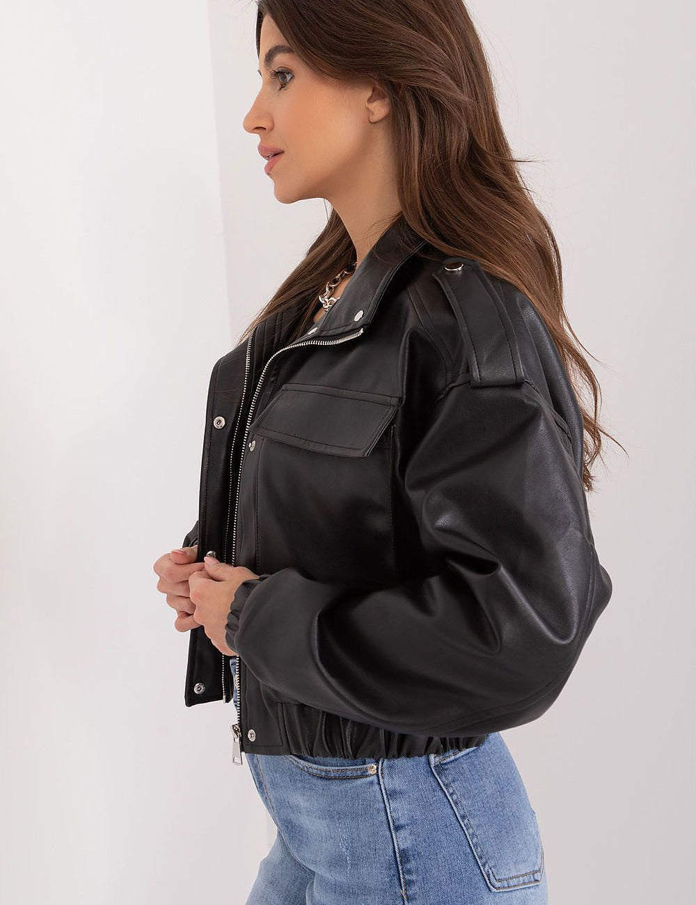 Woman wearing Arvenique eco-leather short jacket with flap pockets and shoulder epaulettes, side profile view.
