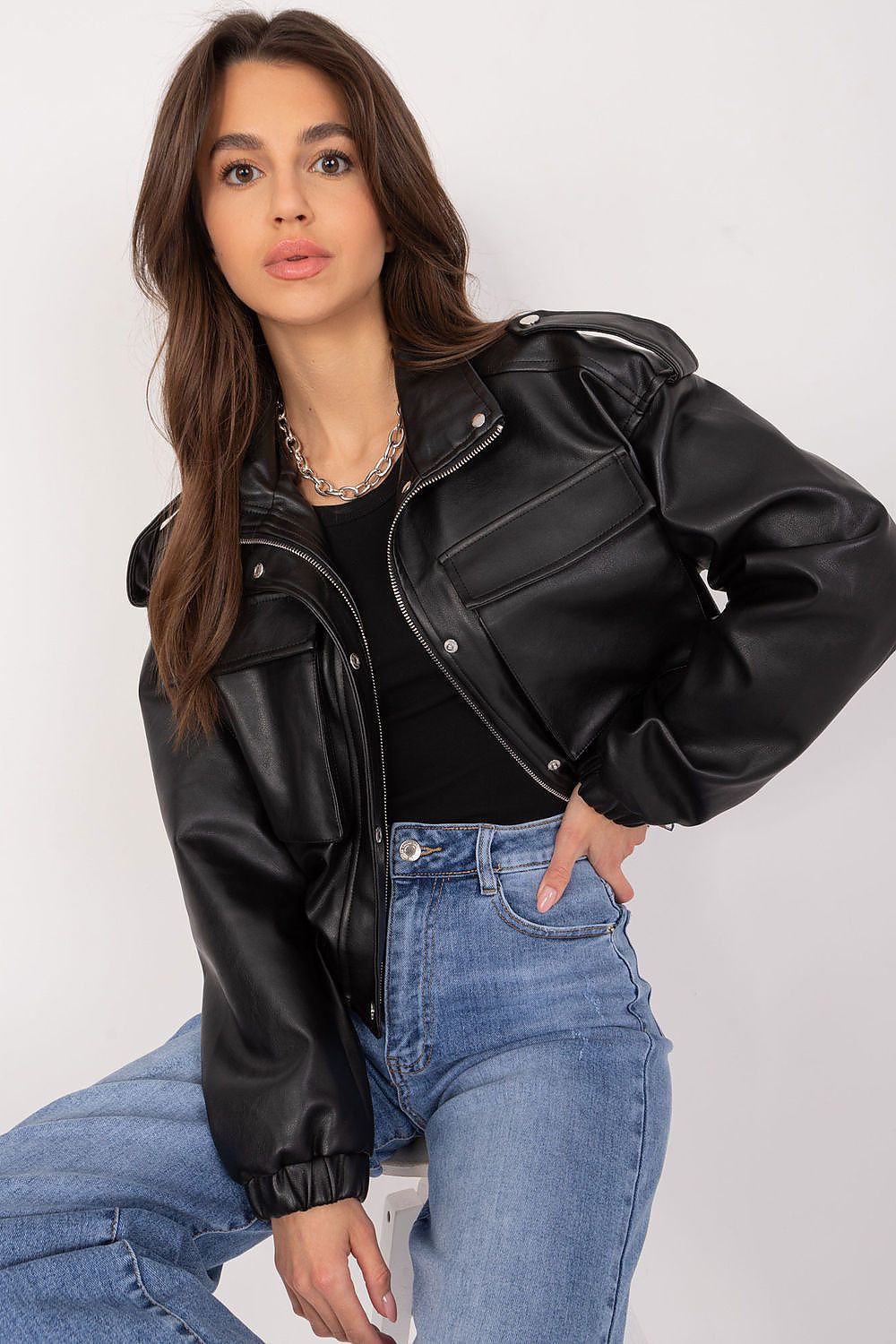 Woman wearing Arvenique eco-leather short jacket with large front flap pockets and shoulder epaulettes, styled with casual jeans.